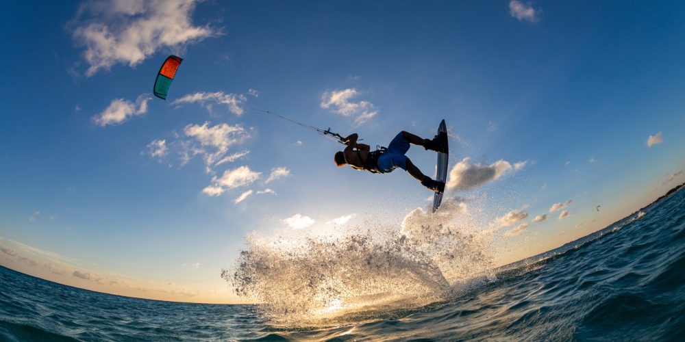 A person surfing and flying a parachute at the same time in Kitesurfing. Bonaire, Caribbean