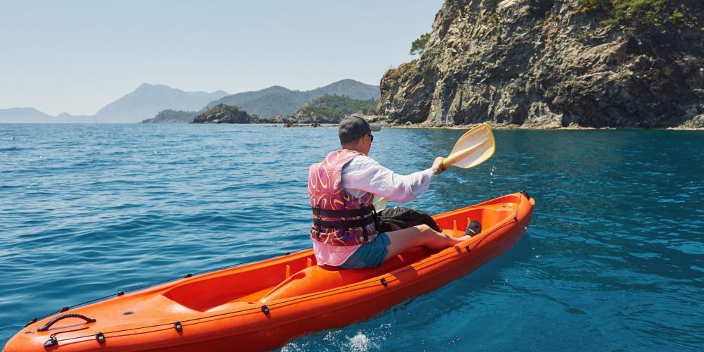 Boat kayaking near cliffs on a sunny day. Travel, sports concept. Lifestyle.